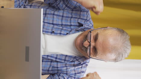Vertical-video-of-Old-man-joyfully-embracing-laptop.